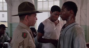 Movie still from “A Soldier's Story” (1984), directed by Norman Jewison – A group of men standing next to each other in front of a window; Medium shot, Over the shoulder angle