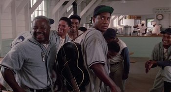 Movie still from “A Soldier's Story” (1984), directed by Norman Jewison – A group of men standing next to each other holding guitars; Medium shot, Low angle