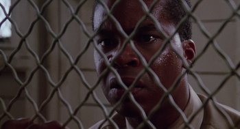 Movie still from “A Soldier's Story” (1984), directed by Norman Jewison – A person behind a chain link fence; Close Up shot, Low angle