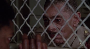 Movie still from “A Soldier's Story” (1984), directed by Norman Jewison – A person behind a chain link fence; Close Up shot, High angle