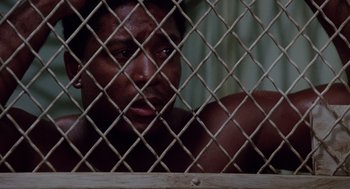 Movie still from “A Soldier's Story” (1984), directed by Norman Jewison – A man looking through a chain link fence; Close Up shot, High angle