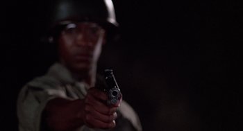Movie still from “A Soldier's Story” (1984), directed by Norman Jewison – A man holding a gun while wearing an army helmet; Close Up shot, Low angle