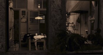 Movie still from “A Special Day” (1977), directed by Ettore Scola – A table and chairs in a room with a plant; Wide shot, High angle