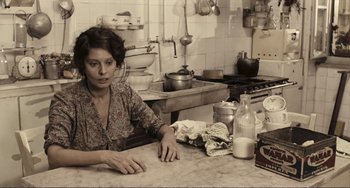 Movie still from “A Special Day” (1977), directed by Ettore Scola – A woman sitting at a counter in a kitchen; Medium shot, High angle