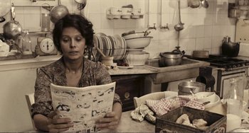 Movie still from “A Special Day” (1977), directed by Ettore Scola – A woman sitting at a kitchen counter reading a magazine; Medium shot, High angle