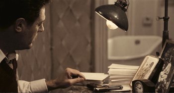 Movie still from “A Special Day” (1977), directed by Ettore Scola – A man sitting at a table with a stack of papers; Medium shot, High angle