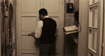 Movie still from “A Special Day” (1977), directed by Ettore Scola – A man standing in front of a door with a phone; Medium shot, High angle