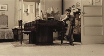 Movie still from “A Special Day” (1977), directed by Ettore Scola – A man sitting on a chair looking at a book; Wide shot, High angle