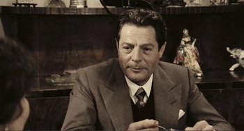 Movie still from “A Special Day” (1977), directed by Ettore Scola – An older man wearing a suit and tie sitting at a table; Close Up shot, Over the shoulder angle