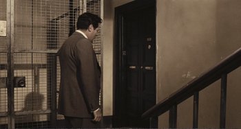 Movie still from “A Special Day” (1977), directed by Ettore Scola – A man in a suit standing in front of a door; Wide shot, High angle