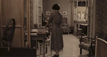 Movie still from “A Special Day” (1977), directed by Ettore Scola – A woman standing in front of a desk with papers on top of it; Wide shot, High angle