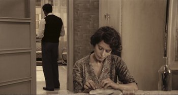 Movie still from “A Special Day” (1977), directed by Ettore Scola – A woman sitting at a table with a man standing in the background; Medium shot, High angle
