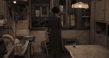Movie still from “A Special Day” (1977), directed by Ettore Scola – A woman standing in front of a window in a kitchen; Wide shot, High angle