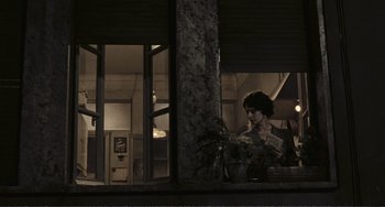 Movie still from “A Special Day” (1977), directed by Ettore Scola – A woman is reading a book in front of a window; Wide shot, High angle