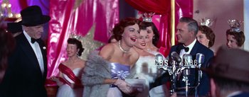 Movie still from “A Star Is Born” (1954), directed by George Cukor – A group of women standing next to each other in a room; Medium shot, Low angle