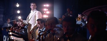 Movie still from “A Star Is Born” (1954), directed by George Cukor – A group of men sitting in front of microphones and saxophones; Medium shot, Low angle