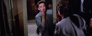 Movie still from “A Star Is Born” (1954), directed by George Cukor – A woman is putting lipstick on in front of a mirror; Close Up shot, Over the shoulder angle