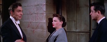 Movie still from “A Star Is Born” (1954), directed by George Cukor – A woman standing in front of a brick wall; Close Up shot, High angle