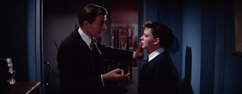 Movie still from “A Star Is Born” (1954), directed by George Cukor – A man and a woman in a suit and tie talking to each other; Medium shot, Over the shoulder angle