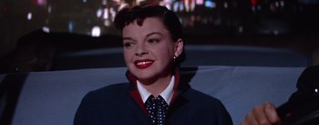 Movie still from “A Star Is Born” (1954), directed by George Cukor – A person wearing a suit and tie; Close Up shot, Low angle