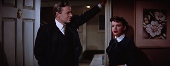 Movie still from “A Star Is Born” (1954), directed by George Cukor – A man and a woman standing next to each other; Medium shot, Low angle