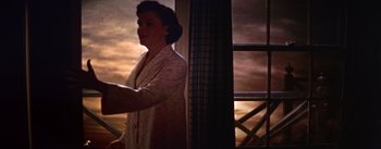 Movie still from “A Star Is Born” (1954), directed by George Cukor – A woman standing in front of a window in the dark; Medium shot, High angle