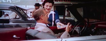 Movie still from “A Star Is Born” (1954), directed by George Cukor – An older man and a woman in a car; Medium shot, High angle