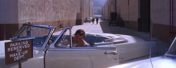 Movie still from “A Star Is Born” (1954), directed by George Cukor – A man sitting in the driver's seat of a car; Wide shot, High angle
