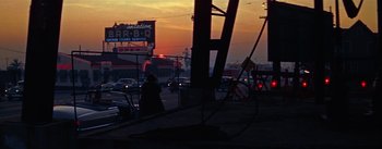 Movie still from “A Star Is Born” (1954), directed by George Cukor – A person walking on the sidewalk near a busy street; Extreme Wide shot, Low angle
