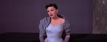 Movie still from “A Star Is Born” (1954), directed by George Cukor – A woman in a blue dress and gloves; Medium shot, Low angle