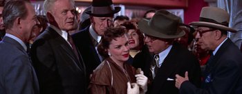 Movie still from “A Star Is Born” (1954), directed by George Cukor – A group of people standing next to each other in a crowd; Medium shot, Over the shoulder angle