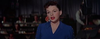 Movie still from “A Star Is Born” (1954), directed by George Cukor – A person wearing a blue shirt; Close Up shot, Over the shoulder angle