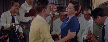 Movie still from “A Star Is Born” (1954), directed by George Cukor – A man and a woman dancing in front of a group of people; Medium shot, High angle