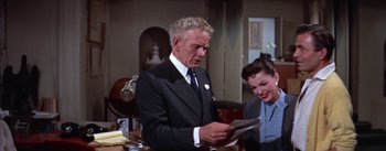 Movie still from “A Star Is Born” (1954), directed by George Cukor – An older man and woman looking at a piece of paper; Medium shot, High angle