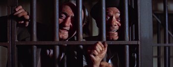 Movie still from “A Star Is Born” (1954), directed by George Cukor – Two old people are behind a metal fence; Close Up shot, Low angle