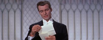 Movie still from “A Star Is Born” (1954), directed by George Cukor – A man in a tuxedo holding a piece of paper in his hands; Close Up shot, Over the shoulder angle