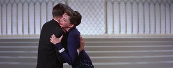 Movie still from “A Star Is Born” (1954), directed by George Cukor – A man and a woman are hugging in a ballroom; Medium shot, High angle