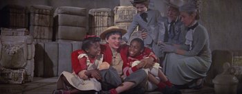 Movie still from “A Star Is Born” (1954), directed by George Cukor – A group of people sitting on the ground; Medium shot, High angle