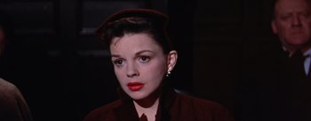Movie still from “A Star Is Born” (1954), directed by George Cukor – A person wearing a suit and hat; Close Up shot, Low angle