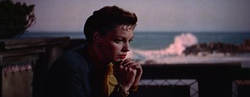Movie still from “A Star Is Born” (1954), directed by George Cukor – A beautiful woman sitting on top of a bench; Close Up shot, High angle