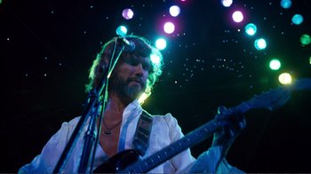 Movie still from “A Star Is Born” (1976), directed by Frank Pierson – A man with a beard is holding a guitar; Medium shot, Low angle