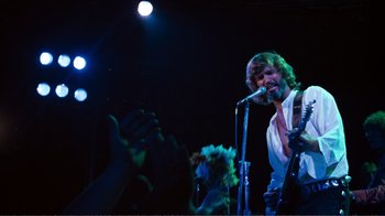 Movie still from “A Star Is Born” (1976), directed by Frank Pierson – A man singing into a microphone on a stage; Medium shot, Low angle