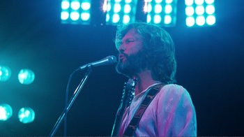 Movie still from “A Star Is Born” (1976), directed by Frank Pierson – A man with long hair and a beard singing into a microphone; Medium shot, Low angle