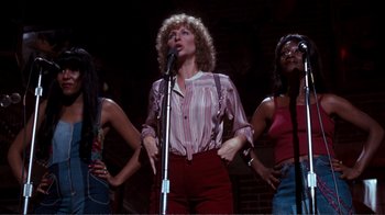 Movie still from “A Star Is Born” (1976), directed by Frank Pierson – A group of women singing into microphones in front of a brick wall; Medium shot, Low angle
