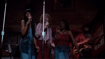 Movie still from “A Star Is Born” (1976), directed by Frank Pierson – A group of people singing into microphones; Wide shot, High angle