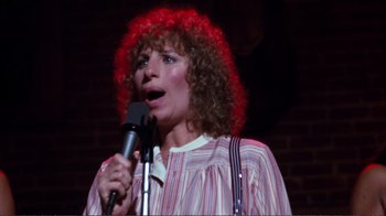 Movie still from “A Star Is Born” (1976), directed by Frank Pierson – A woman in a red wig singing into a microphone; Close Up shot, High angle