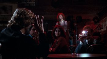 Movie still from “A Star Is Born” (1976), directed by Frank Pierson – A group of people sitting at a table; Medium shot, Over the shoulder angle