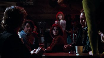 Movie still from “A Star Is Born” (1976), directed by Frank Pierson – A group of people sitting at a table with drinks; Medium shot, Over the shoulder angle