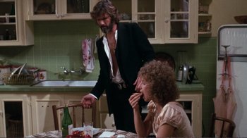 Movie still from “A Star Is Born” (1976), directed by Frank Pierson – A man and a woman are eating at a dinner table; Medium shot, Over the shoulder angle