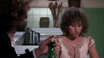 Movie still from “A Star Is Born” (1976), directed by Frank Pierson – A man and a woman in a kitchen holding a bottle; Close Up shot, Over the shoulder angle